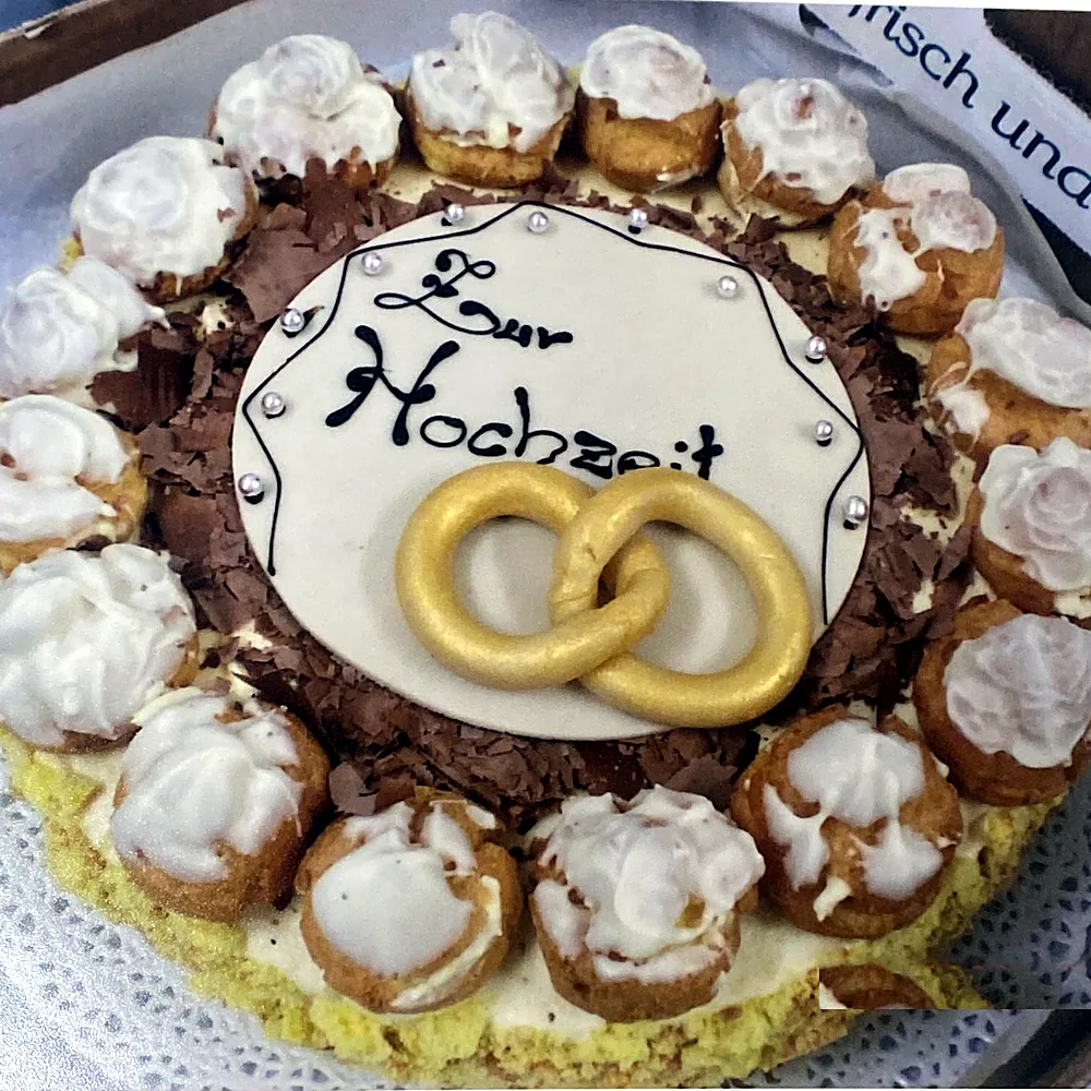 Hochzeitstorte mit goldenen Eheringen und Windbeuteln